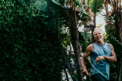 Mark smiles mid-stride in front of a grove of trees.