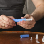 Man sitting in front of coffee table preparing Semaglutide Ozempic injection.