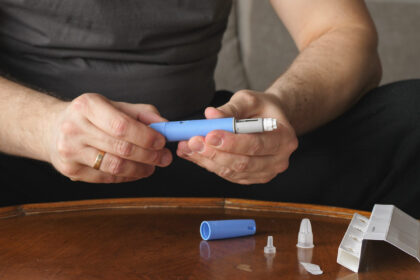 Man sitting in front of coffee table preparing Semaglutide Ozempic injection.