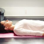 Woman laying on back on pink yoga mat