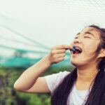 Teenage girl happily eating fresh blueberries