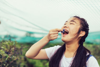 Teenage girl happily eating fresh blueberries