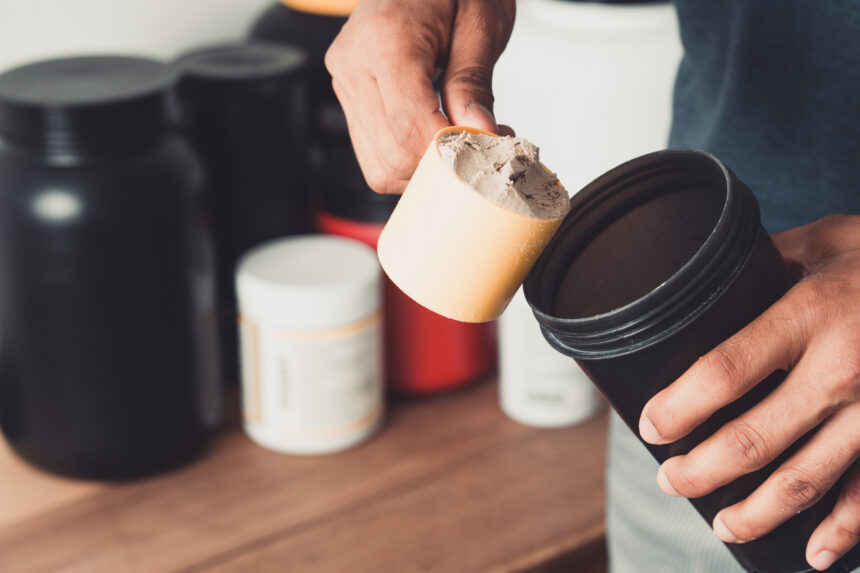 Hands holding scoop of protein powder and shaker