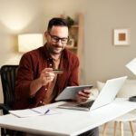 Man on laptop holding a credit card