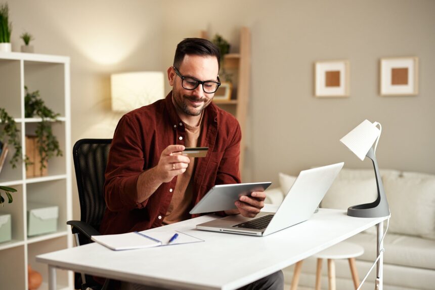 Man on laptop holding a credit card