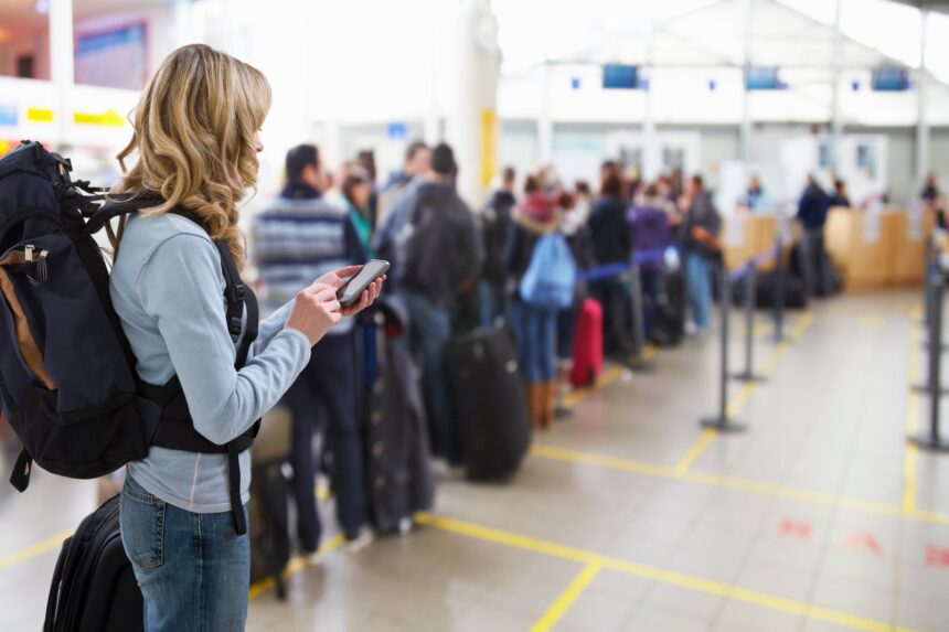 female traveller texting at airport check-in desk