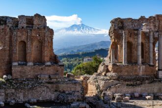 Volcano Etna in Sicily seen through ruins of ancient amphitheater in Taormina