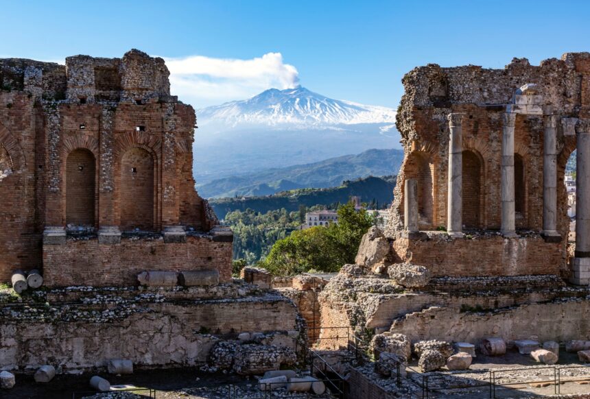 Volcano Etna in Sicily seen through ruins of ancient amphitheater in Taormina