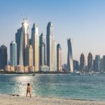 Woman walking on beach in front of Dubai skyline