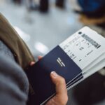 Woman‚Äôs hands holding passports &amp; boarding passes of her family while waiting at the check-in counter in the airport