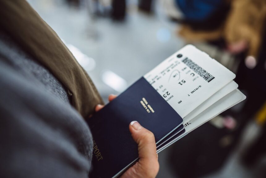 Woman‚Äôs hands holding passports &amp; boarding passes of her family while waiting at the check-in counter in the airport