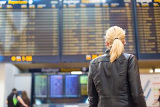 Female traveller checking flight departures board.