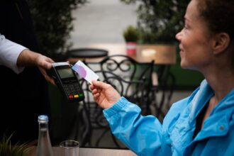 Happy young woman paying for her coffee by a credit card