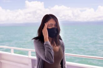 Woman suffering from sea sickness and feeling headache while on boat