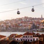 Cable car cabins moving above Porto city and Douro river at sunset, Portugal