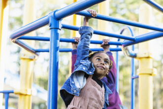 girl playing on playground monkey bars