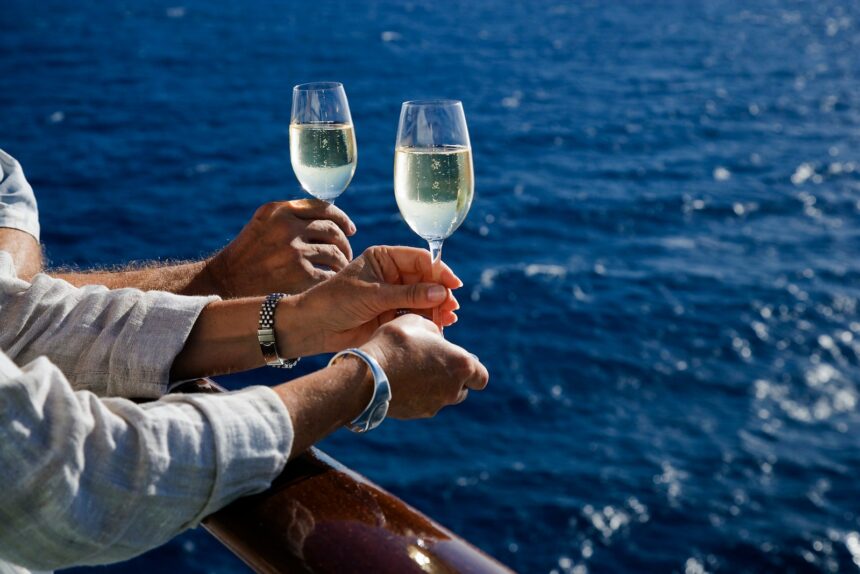 Hands holding champagne glass on cruise ship