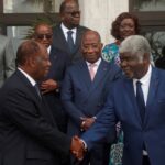 Alassane Ouattara shakes hands with the new prime minister, Robert Beugré Mambé, at the new government