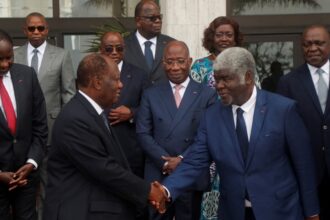 Alassane Ouattara shakes hands with the new prime minister, Robert Beugré Mambé, at the new government