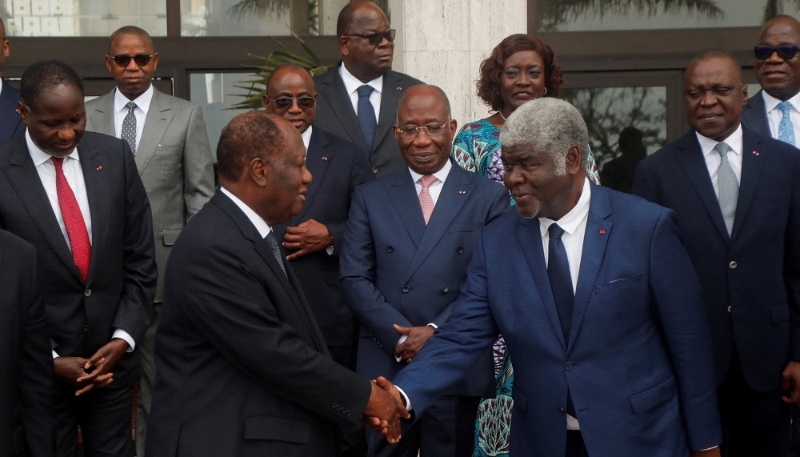 Alassane Ouattara shakes hands with the new prime minister, Robert Beugré Mambé, at the new government