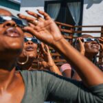 Women friends at home enjoying solar eclipse looking at the sun with eclipse sunglasses