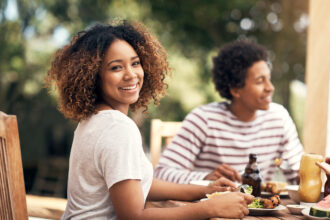 Portrait of a young woman having a meal with friends outdoors.