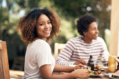Portrait of a young woman having a meal with friends outdoors.