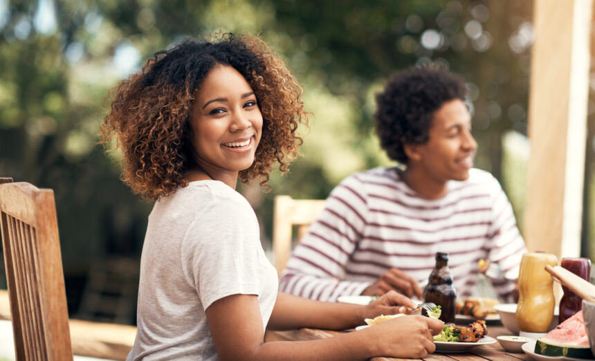 Portrait of a young woman having a meal with friends outdoors.