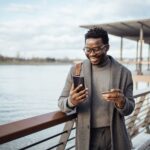 Afro american businessman using smart phone on city street