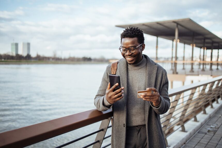 Afro american businessman using smart phone on city street