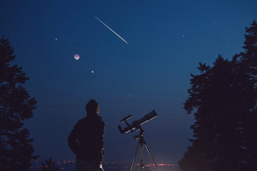 Silhouette of a man, telescope, stars, planets and shooting star under the night sky.