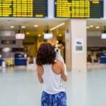 traveler woman and her dog at the airport. information screens background. travel and transportation with technology concept.